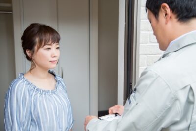 業者の人が玄関先で家主に質問している